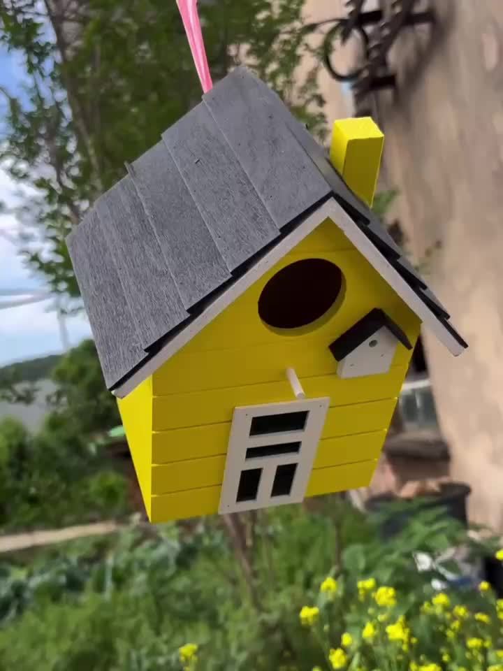 Nichoir coloré Spring Melody en bois léger suspendu dans un jardin fleuri, accueillant des mésanges et des bleuets.